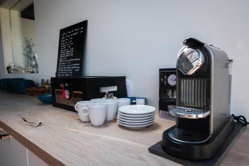 a coffee machine sitting on a counter with cups and plates at Rue Haute by M&M 4 sterren bed en breakfast vlakbij Maastricht in Eben-Emael