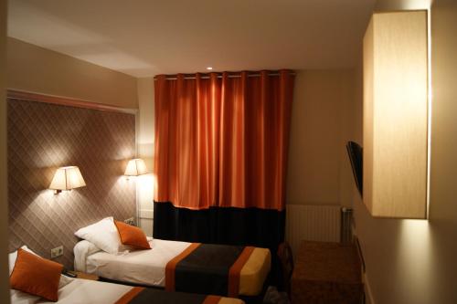 a hotel room with two beds and an orange curtain at Hotel d'Amiens in Paris