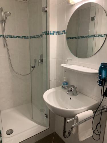 a bathroom with a sink and a shower with a mirror at Hotel-Restaurant Haus Waldesruh in Borken