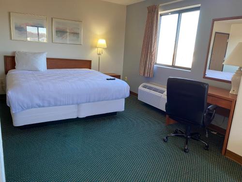 Carlyle的住宿－Carlyle Inn & Suites，酒店客房配有一张床、一张桌子和一把椅子。