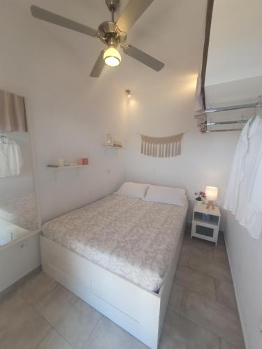 a white bedroom with a bed and a ceiling fan at Antiparos Vibes in Agios Georgios