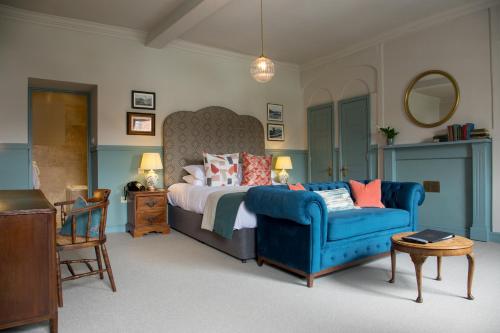 a bedroom with a bed and a blue couch at The Hoste and The Vine House Hotels in Burnham Market