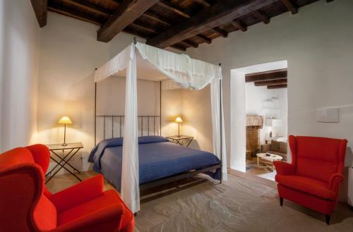 1 dormitorio con 1 cama con dosel y 2 sillas rojas en Il Castello di Campello, en Campello sul Clitunno