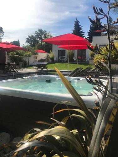 a swimming pool with a red umbrella and a house at Villa le sud appartements in Cassis