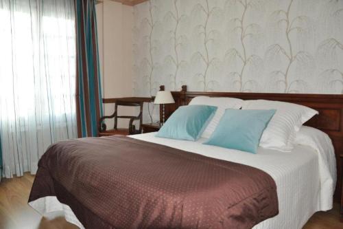 1 dormitorio con 1 cama grande con almohadas azules en Hotel Edelweiss en Camprodon