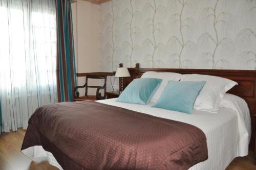 a bedroom with a large bed with blue pillows at Hotel Edelweiss in Camprodon