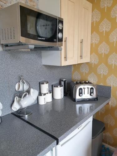 a kitchen with a counter top with a microwave at Millie's place in Fort William