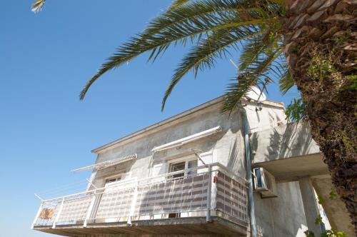 un edificio bianco con balcone e palma di Apartments Mira a Splitska