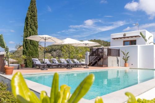 a villa with a swimming pool with chairs and umbrellas at Can Skye in Sant Carles de Peralta
