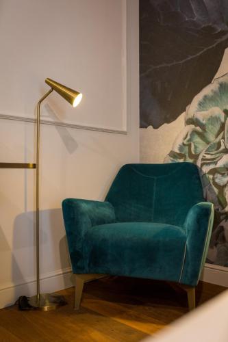 a green chair in a living room with a lamp at Palazzo 42 - Boutique Hotel & Suites in Pistoia