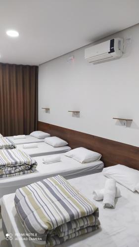 a row of beds in a room at Flat familiar com ar,wi fi,cozinha e garagem in Aparecida