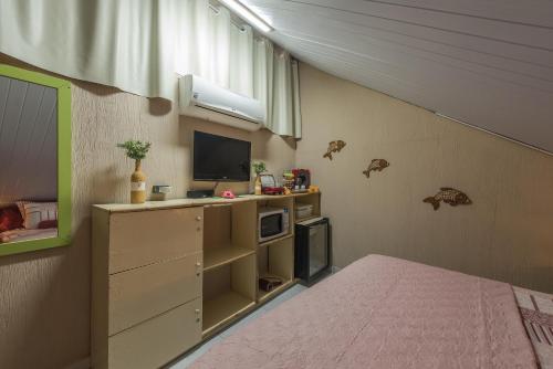 a room with a bed and a tv and a bed gmaxwell gmaxwell gmaxwell at Doce Lar Hostel Noronha in Fernando de Noronha