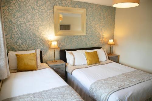 two beds in a room with a mirror and two lamps at Arch House B&B & Apartments in Athlone