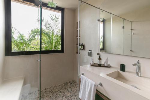 uma casa de banho com um chuveiro, um lavatório e um espelho. em Zereno Boutique Hotel em Tulum