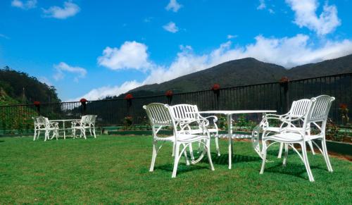 a group of white chairs and a table in the grass at The Wind Castle in Nuwara Eliya