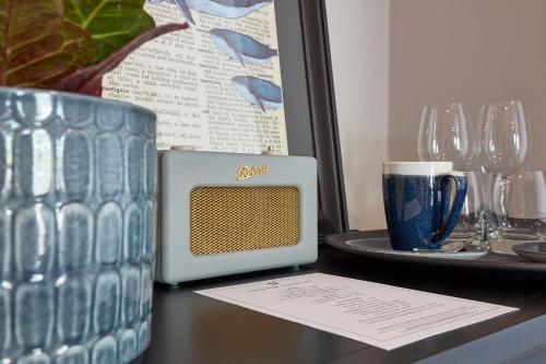 a table with a clock and a plate of wine glasses at The Hoste and The Vine House Hotels in Burnham Market