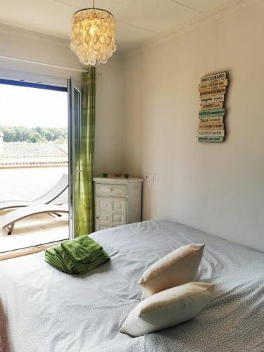 a bedroom with a bed with a window and a chandelier at Villa Valerie bio & zen in L'Escala
