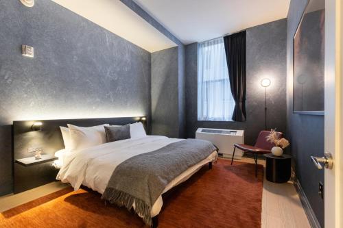 a bedroom with a large bed with a gray wall at Mint House at 70 Pine in New York