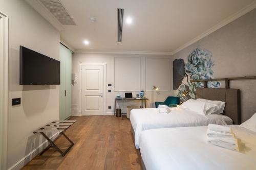a hotel room with two beds and a flat screen tv at Palazzo 42 - Boutique Hotel & Suites in Pistoia