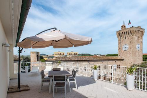 a patio with a table and an umbrella and a clock tower at Fruttadamare in Porto Recanati