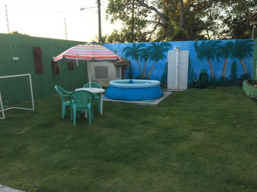 a backyard with a table and an umbrella at Suítes Carapibus in Jacumã