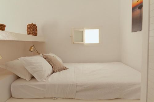 a white bedroom with a bed and a window at Rooftop House in the old town of Parikia - Paros in Parikia