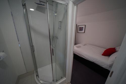 a shower in a small bathroom with a bed at The Bank in Barking