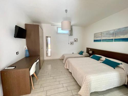 a bedroom with two beds and a desk and a tv at B&b il Patio in Villasimius