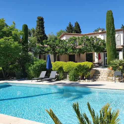 une piscine avec deux chaises et une maison dans l'établissement Le Domaine des Mûriers - charme, chic, calme en Provence Côte d'Azur, à Plascassier