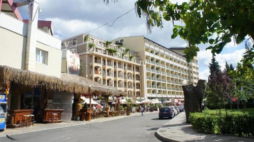 una calle con un edificio, mesas y sillas en Menada Miramar Palace Apartments, en Sunny Beach