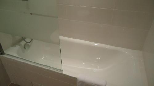 a white bathroom with a shower and a tub at Hotel d'Amiens in Paris