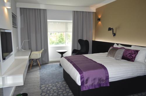 Habitación de hotel con cama y TV en The Golden Jubilee Hotel en Clydebank