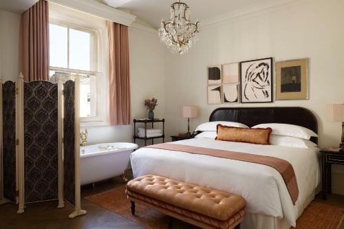 ロンドンにあるNoMad Londonのベッドルーム1室(ベッド1台、バスタブ、シャンデリア付)