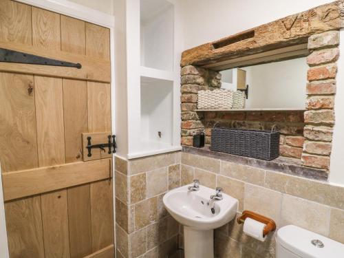 a bathroom with a sink and a toilet and a mirror at Pollard Cottage in Northallerton