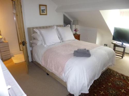 um quarto com uma cama grande e almofadas brancas em Cranberry Cottage em Wallingford