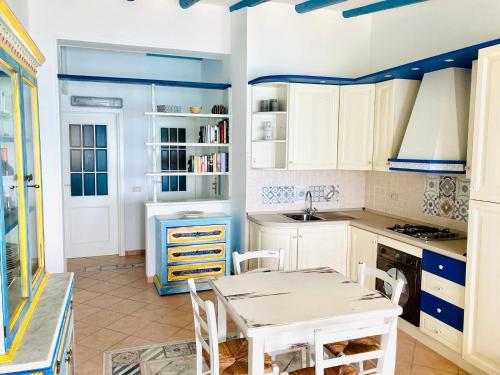 a kitchen with white cabinets and a table and chairs at Sea View Appartment with bicycles and stand-up paddle in Capo dʼOrlando