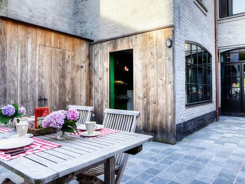 a wooden table with chairs and flowers on a patio at Menin Gate House in Ypres