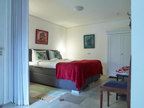 a bedroom with a bed with a red blanket at Studio # Het Pauwennest in Den Bosch
