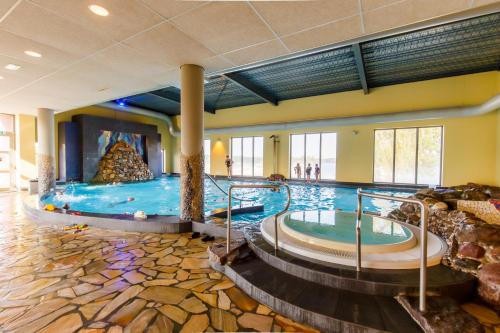 een groot zwembad met 2 hot tubs in een hotelkamer bij Vakantiepark Leukermeer in Well
