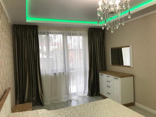 a bedroom with a bed and a mirror and a chandelier at Квартира 3-комнатная ЛЮКС in Sukhum