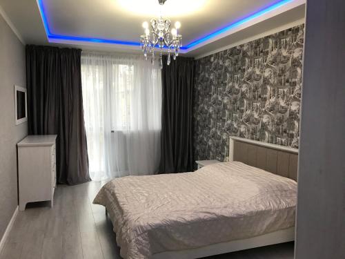 a bedroom with a bed and a chandelier at Квартира 3-комнатная ЛЮКС in Sukhum