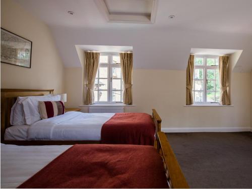 a bedroom with two beds and two windows at Lord High Admiral in Winchcombe