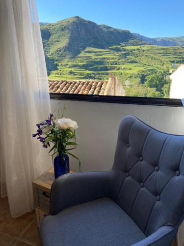 a blue chair and a vase with flowers in a window at Casa El calado in Viguera