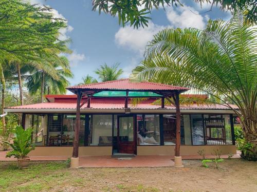a house with a red roof with palm trees at Tranquilidad Resort in Parrita