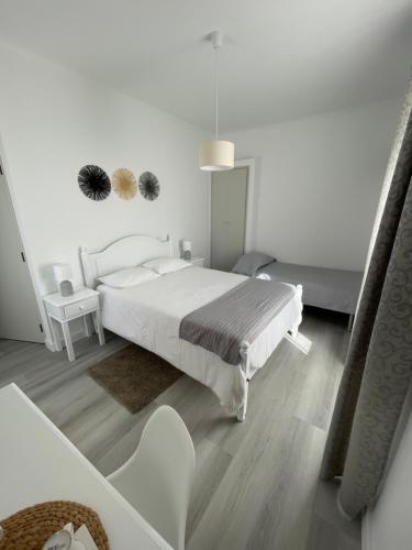 a white bedroom with a white bed and a table at Casa de Hospedes D. Maria Parreirinha in Sintra