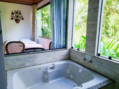 a bath tub in a room with two windows at Pousada Mirante do Penedo in Penedo