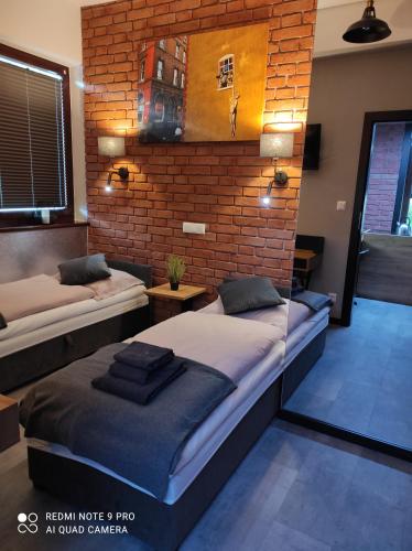 1 dormitorio con 2 camas y pared de ladrillo en Apartament Aurora Kletno, en Stronie Śląskie