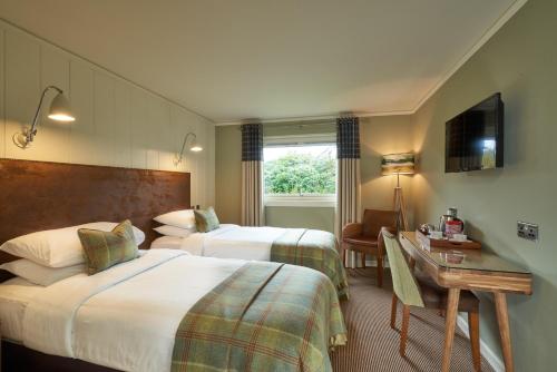 a hotel room with two beds and a desk at Isle Of Mull Hotel and Spa in Craignure