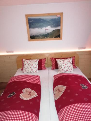 two beds in a room with red and white pillows at Zachhof in Ellbögen