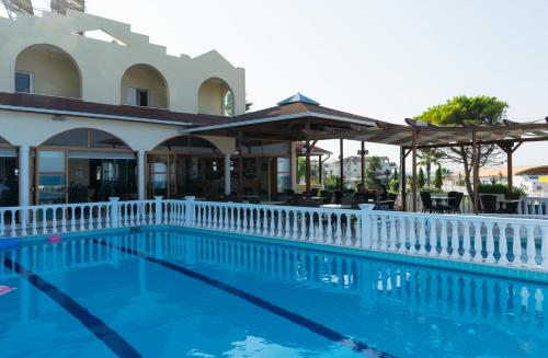 Katerina Hotel في كانالي: مسبح بسياج ابيض بجانب مبنى